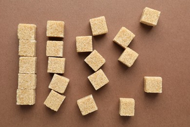 Brown sugar cubes on color background, top view