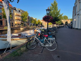 Leiden, Netherlands - August 1, 2022: Picturesque view of city street with parked bicycles and beautiful buildings along canal