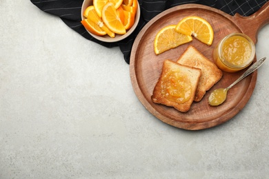 Delicious toasts with orange marmalade on light grey table, flat lay. Space for text