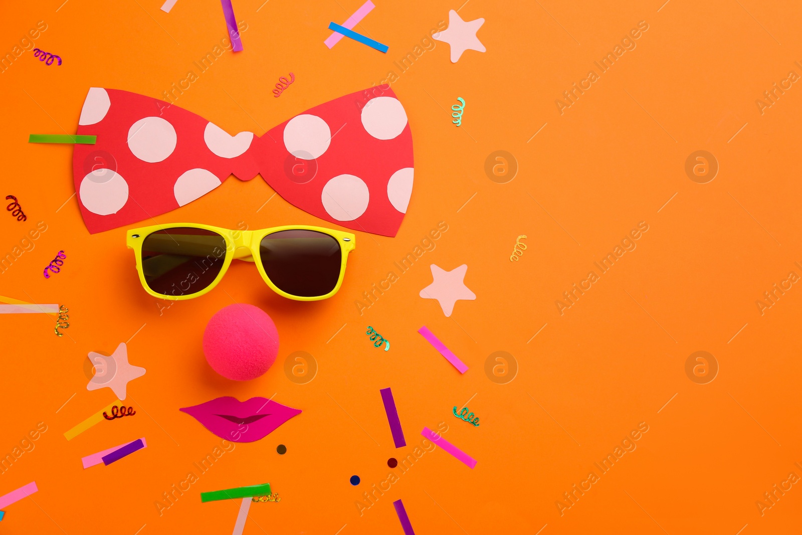 Photo of Flat lay composition with clown's face made of sunglasses and bow on orange background, space for text