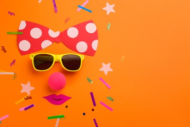 Photo of Flat lay composition with clown's face made of sunglasses and bow on orange background, space for text