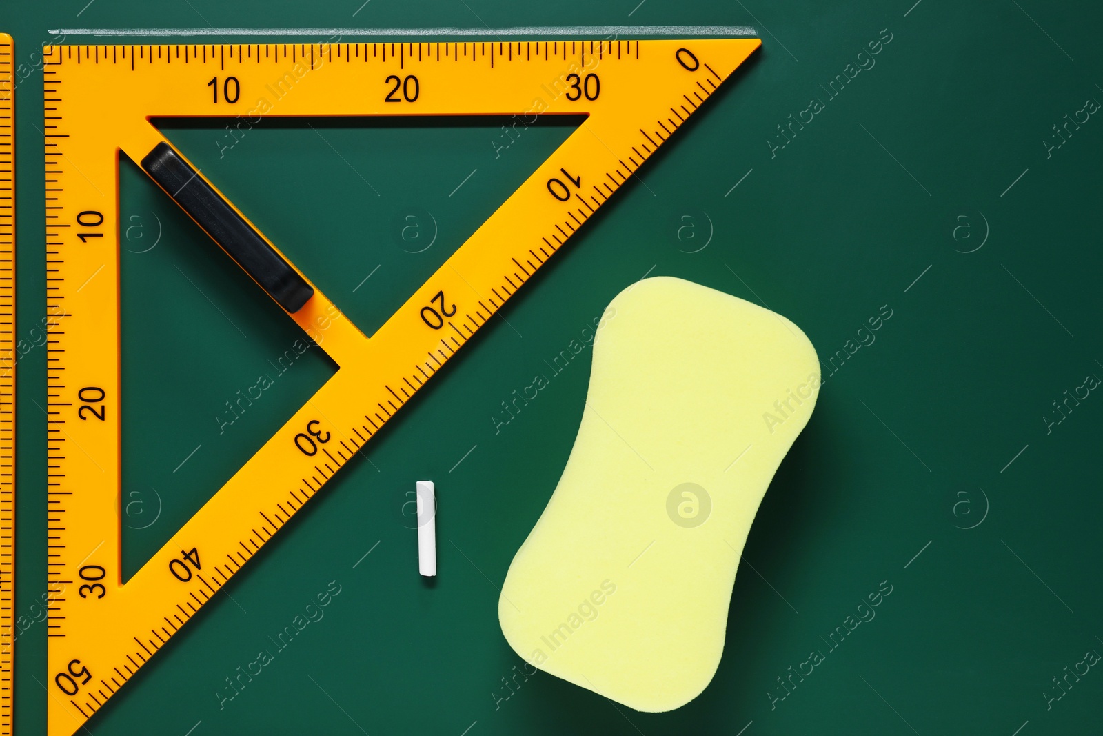 Photo of Protractor, sponge, chalk and ruler on green chalkboard, flat lay