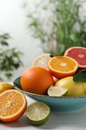 Different cut and whole citrus fruits on white wooden table outdoors