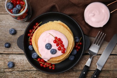 Photo of Tasty pancakes with natural yogurt, blueberries and red currants on wooden table, flat lay
