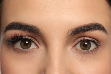 Photo of Beautiful young woman showing extended and ordinary eyelashes, closeup