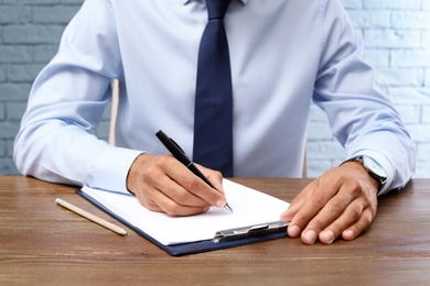 Photo of Male lawyer working with documents at table, closeup. Notary services