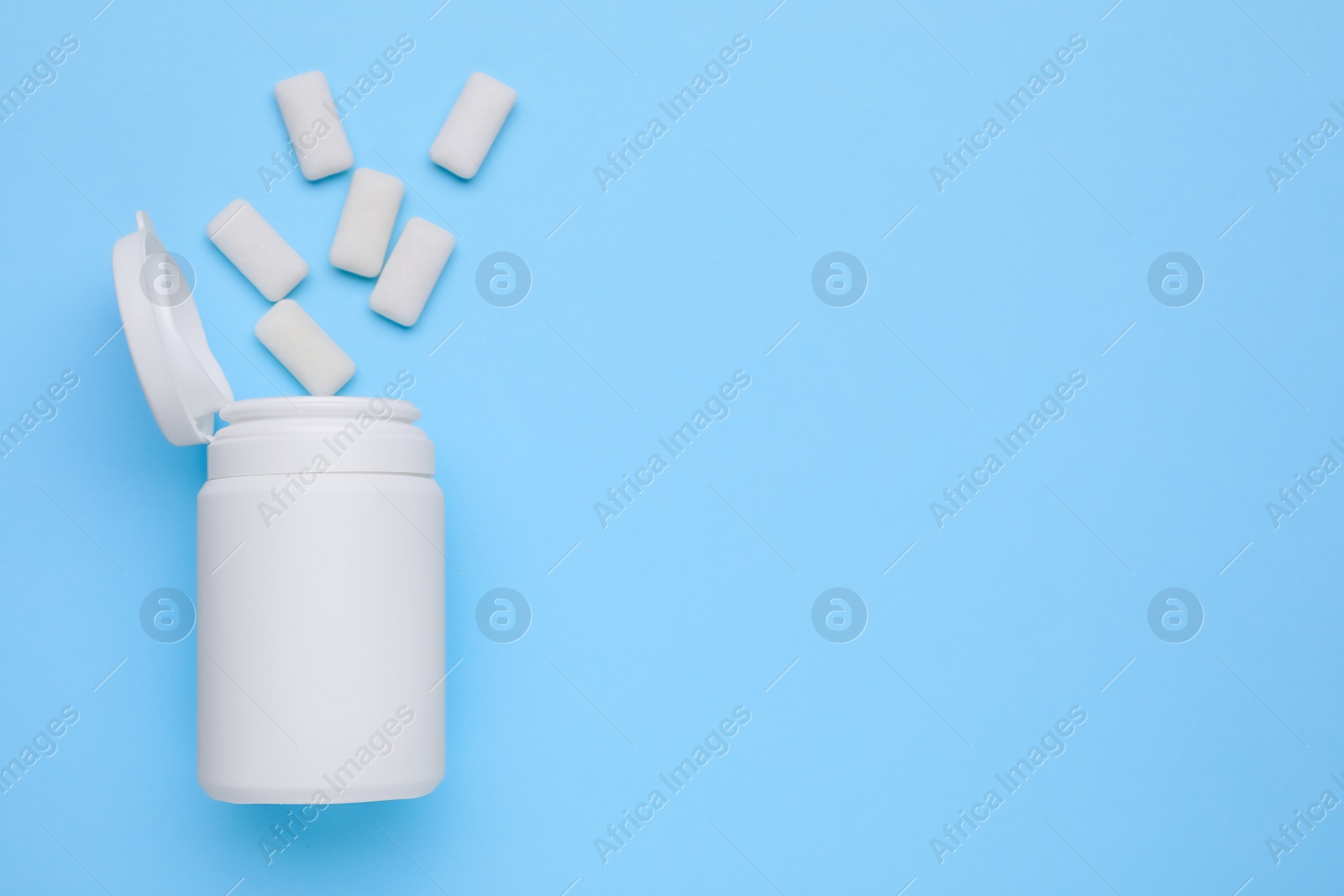 Photo of Jar with chewing gums on light blue background, flat lay. Space for text