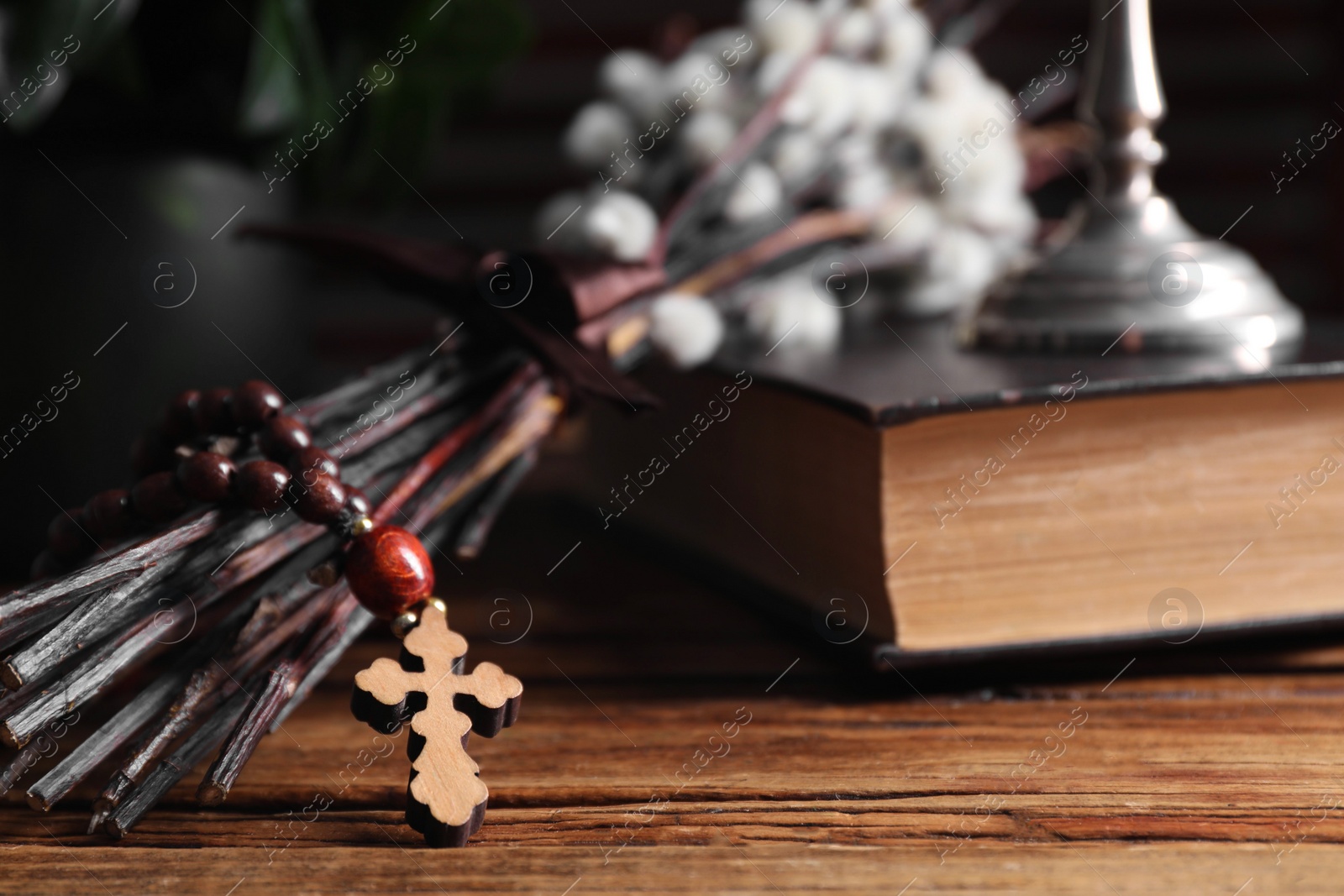 Photo of Rosary beads, Bible and willow branches on wooden table, closeup