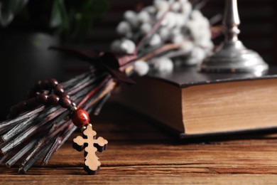 Photo of Rosary beads, Bible and willow branches on wooden table, closeup