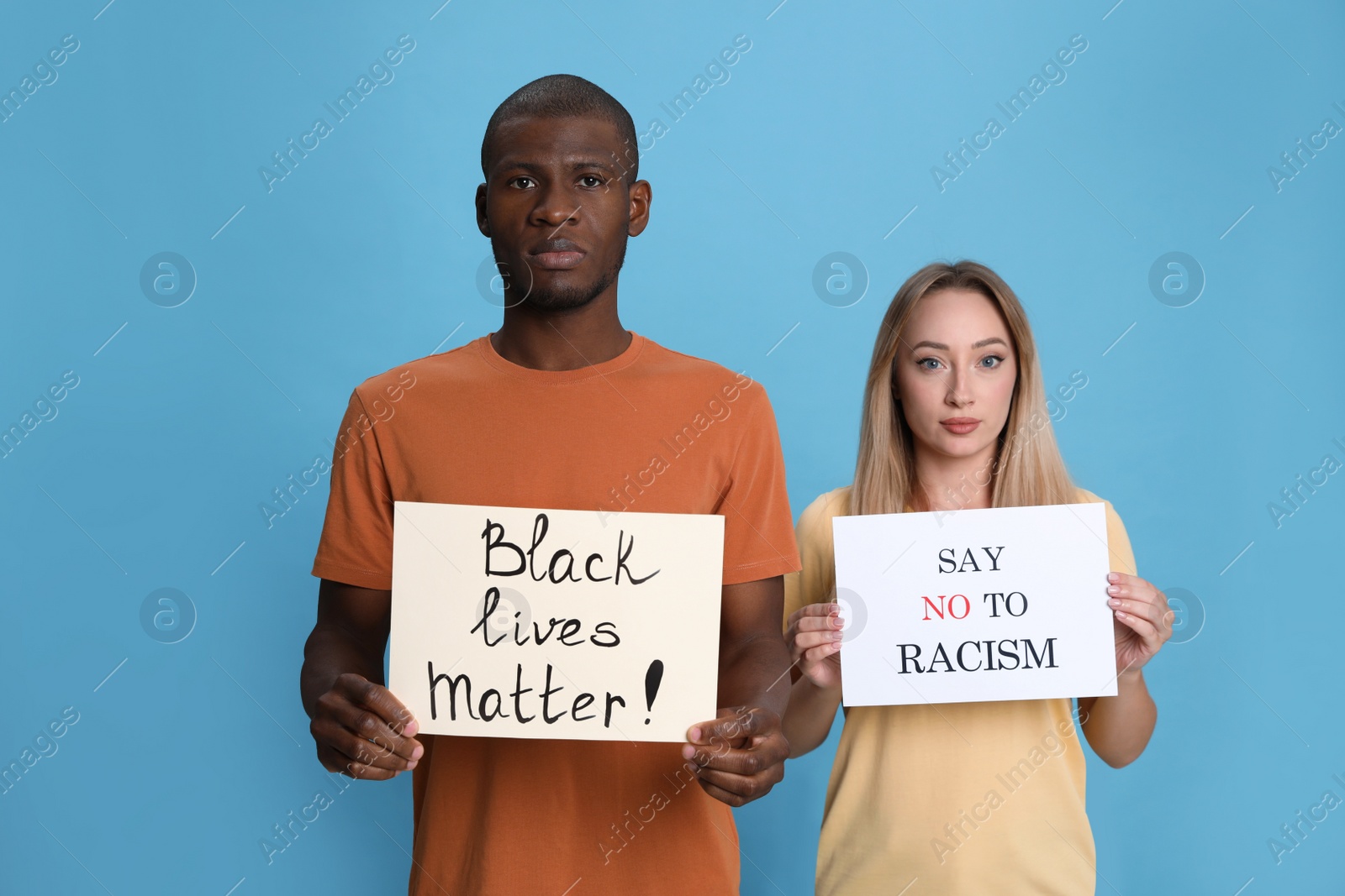 Photo of Young woman and African American man holding signs on light blue background. Racism concept