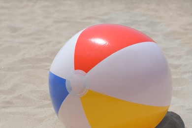 Photo of Colorful beach ball on sand, closeup view