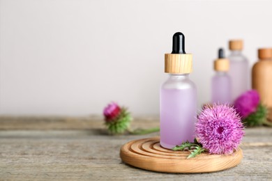 Photo of Bottle of essential oil and flower on wooden table. Space for text