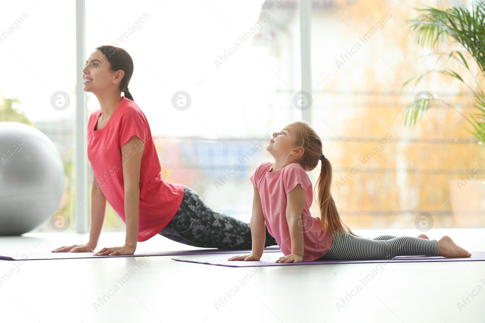 Photo of Woman and daughter doing yoga together at home. Fitness lifestyle