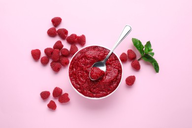 Photo of Raspberry puree in bowl and fresh berries with mint on pink background, flat lay