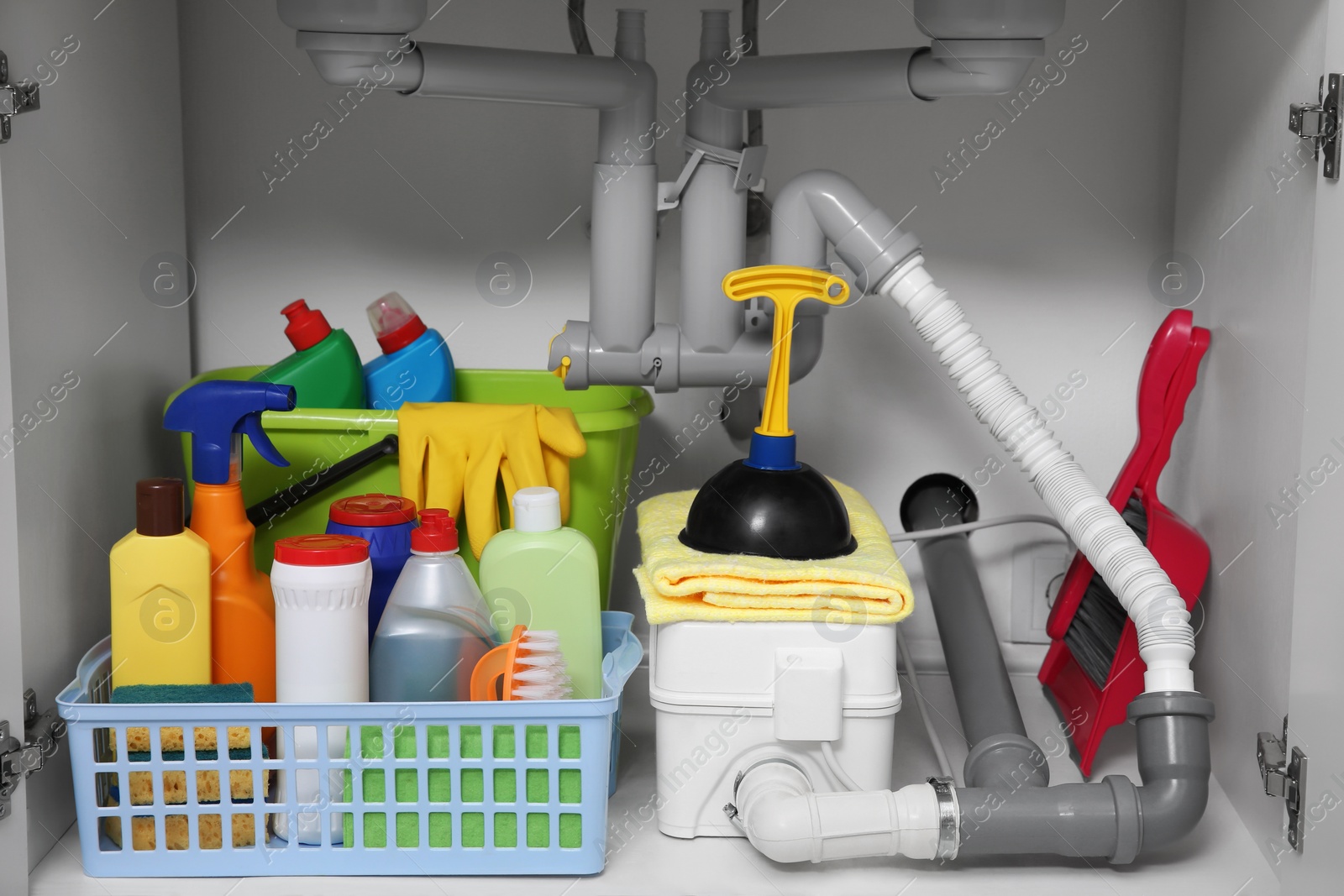 Photo of Open under sink cabinet with different cleaning supplies in kitchen