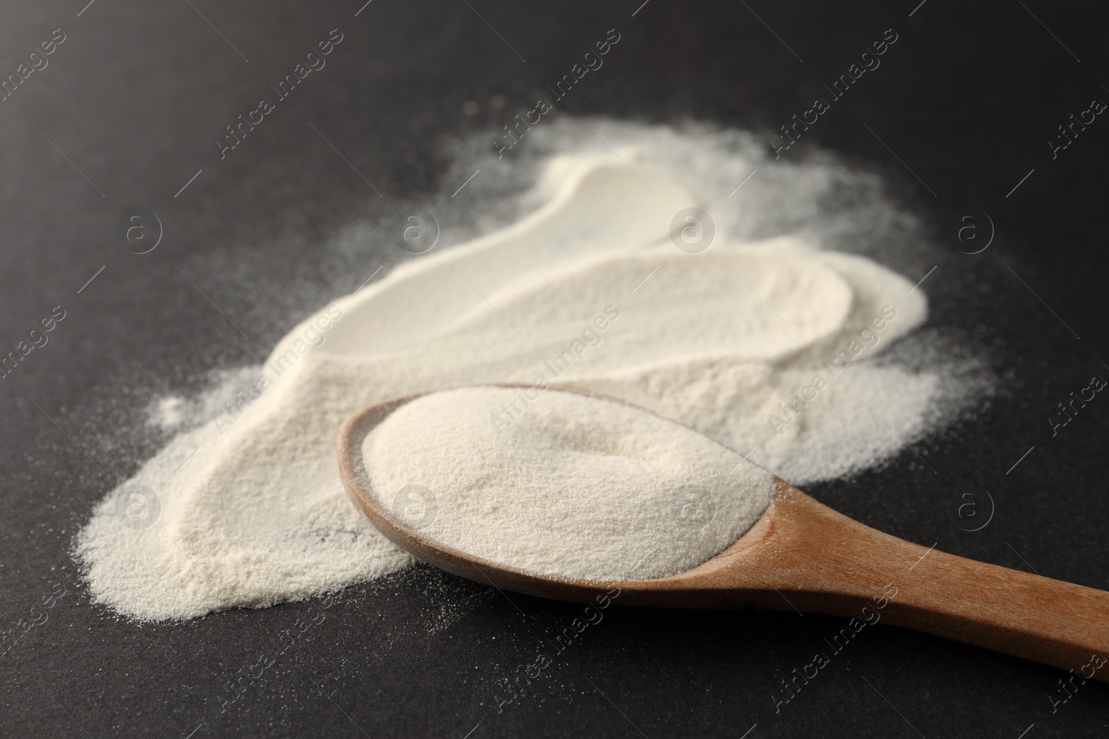 Photo of Spoon of agar-agar powder on black background, closeup