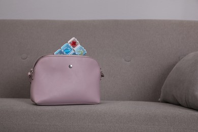 Photo of Stylish women's bag with plastic pill box on sofa indoors. Space for text