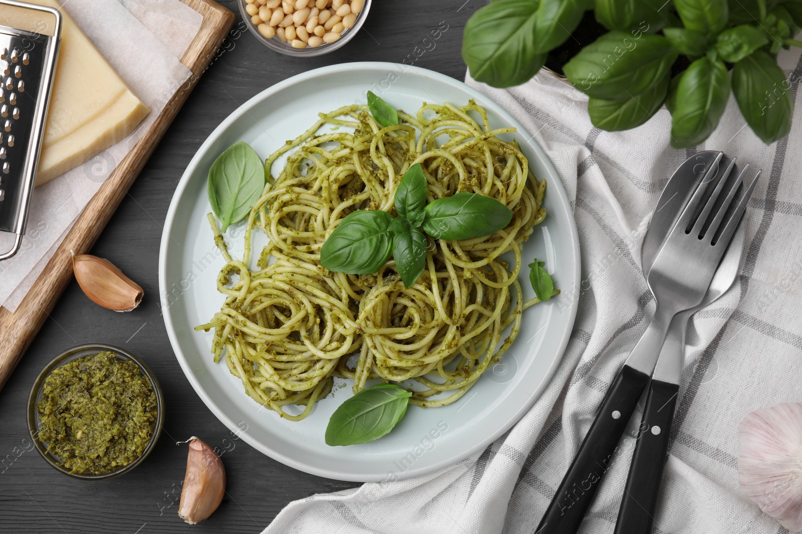 Photo of Delicious pasta with pesto sauce and basil served on grey wooden table, flat lay