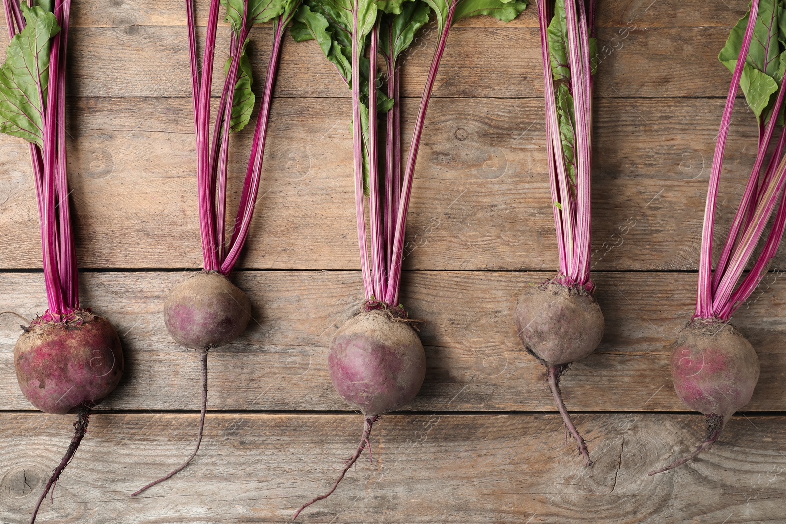 Photo of Raw ripe beets on wooden table, flat lay