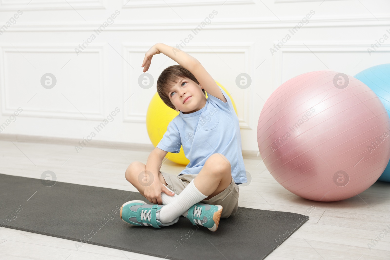 Photo of Boy doing gymnastic exercises on mat indoors