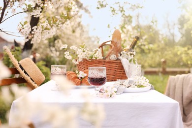 Stylish table setting with beautiful spring flowers, wine and croissants in garden