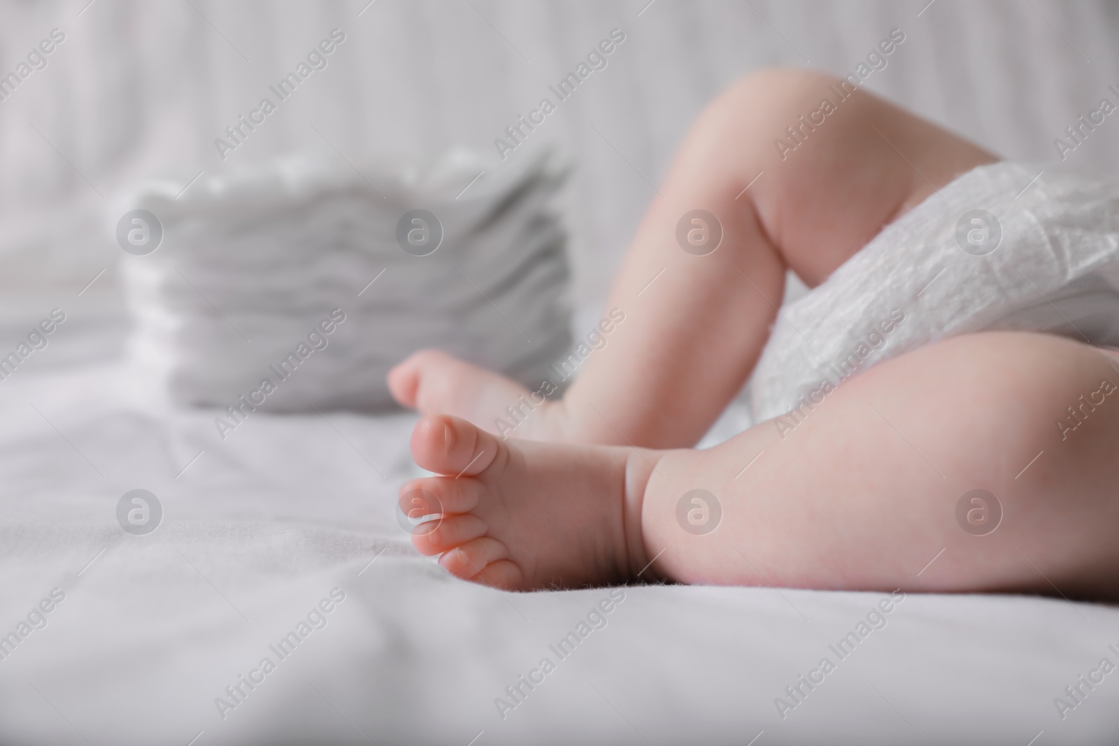 Photo of Little baby in diaper lying on bed, closeup