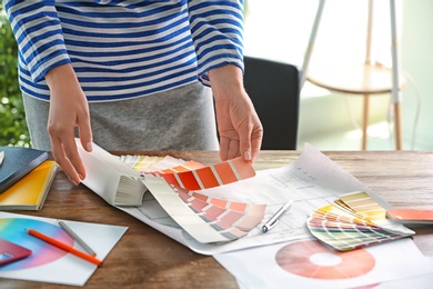 Photo of Female designer working with color palette samples at table