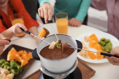 Photo of Family having fondue dinner at table, closeup