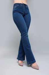 Woman in stylish jeans on grey background, closeup