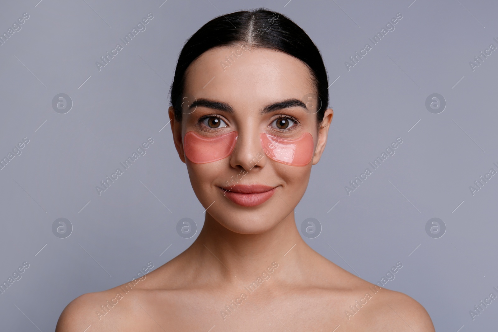 Photo of Beautiful young woman with under eye patches on grey background