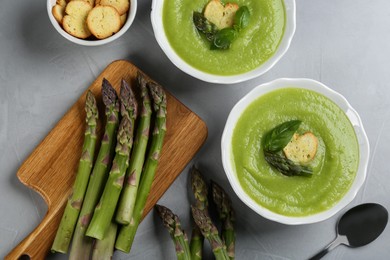 Photo of Delicious asparagus soup served on grey table, flat lay