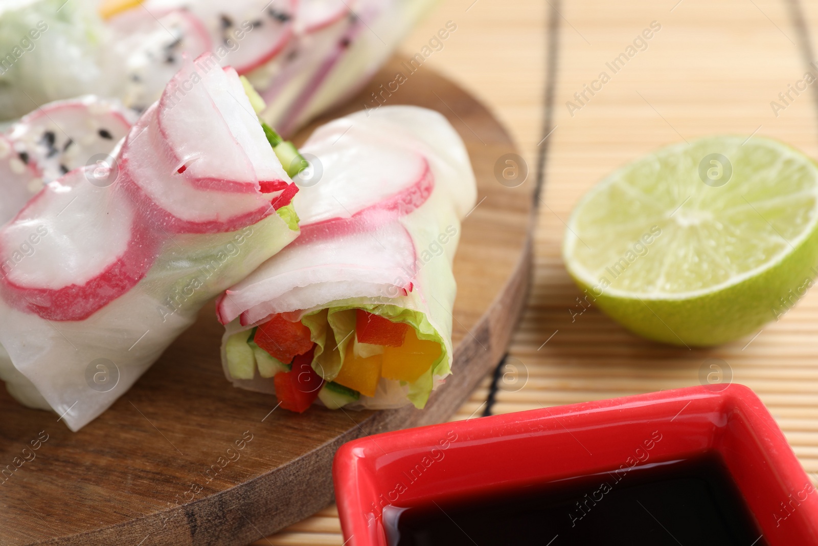 Photo of Delicious spring rolls, lime and soy sauce on table, closeup