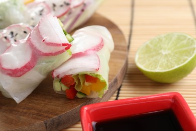 Delicious spring rolls, lime and soy sauce on table, closeup