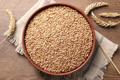 Wheat grains and spikes on wooden table, flat lay