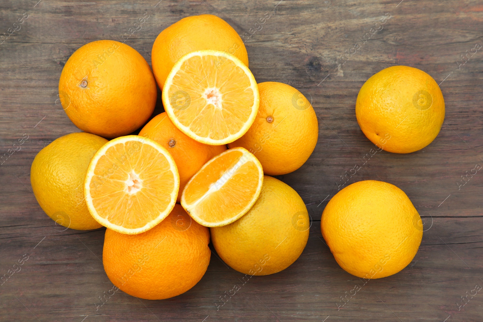 Photo of Many whole and cut oranges on wooden table, flat lay