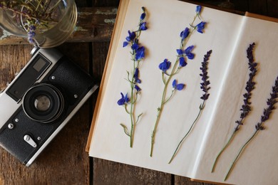 Photo of Flat lay composition with beautiful dried flowers and vintage camera on wooden table