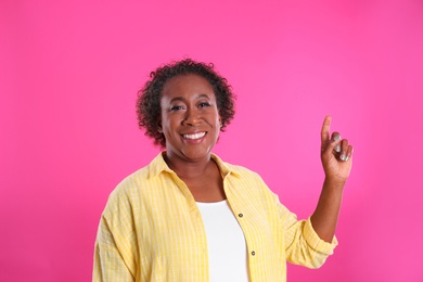 Photo of Portrait of happy African-American woman on pink background