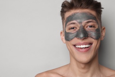 Photo of Handsome man with clay mask on his face against light grey background. Space for text