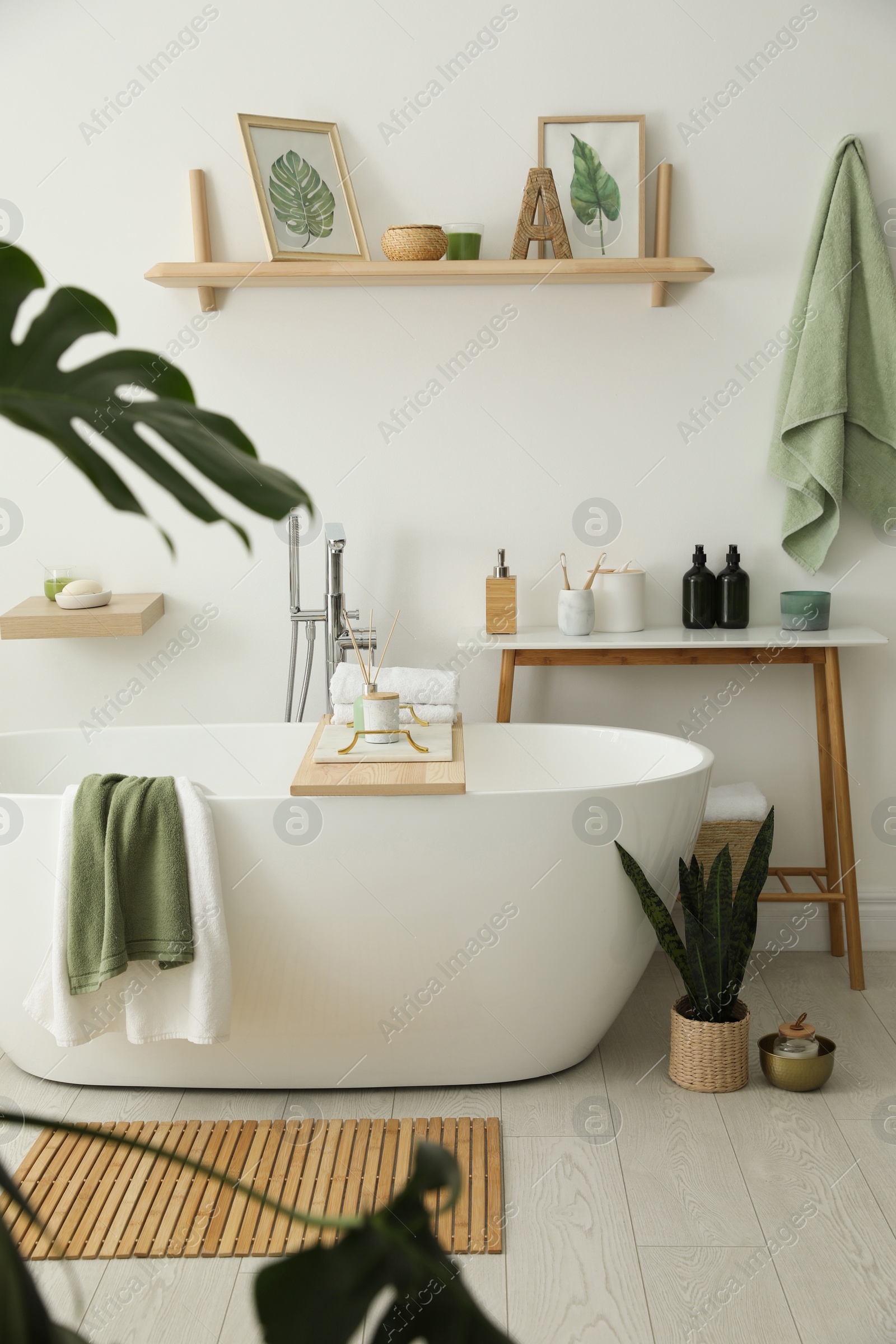 Photo of Stylish bathroom interior with modern tub, houseplants and beautiful decor. Home design