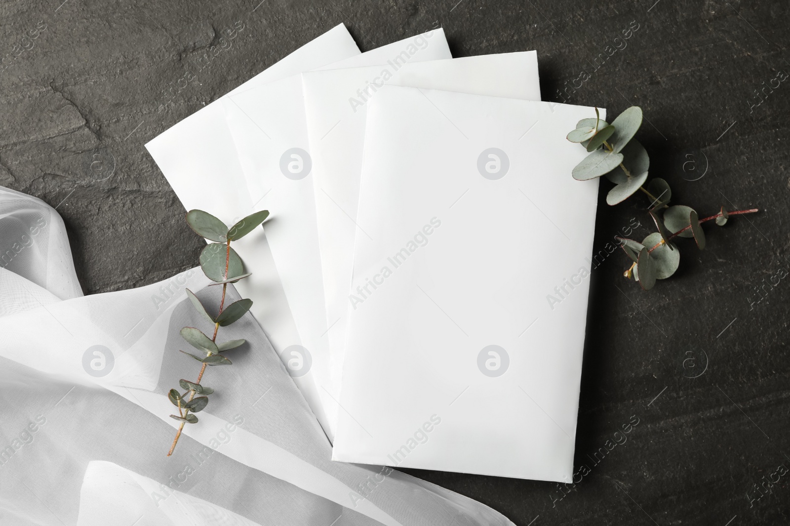 Photo of Scented sachets, eucalyptus branches and fabric on black table, flat lay