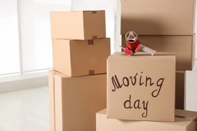 Photo of Pile of moving boxes and adhesive tape indoors, closeup