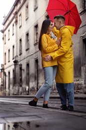 Photo of Lovely young couple with red umbrella together on city street
