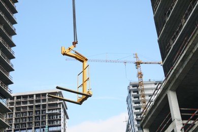 Photo of Tower crane near unfinished buildings against cloudy sky on construction site