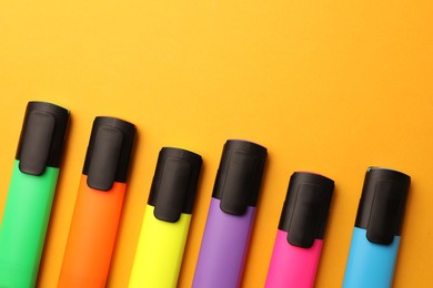 Photo of Bright markers on orange background, flat lay. Space for text