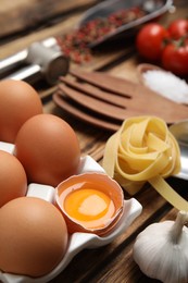 Eggs, raw pasta and garlic on wooden table, closeup