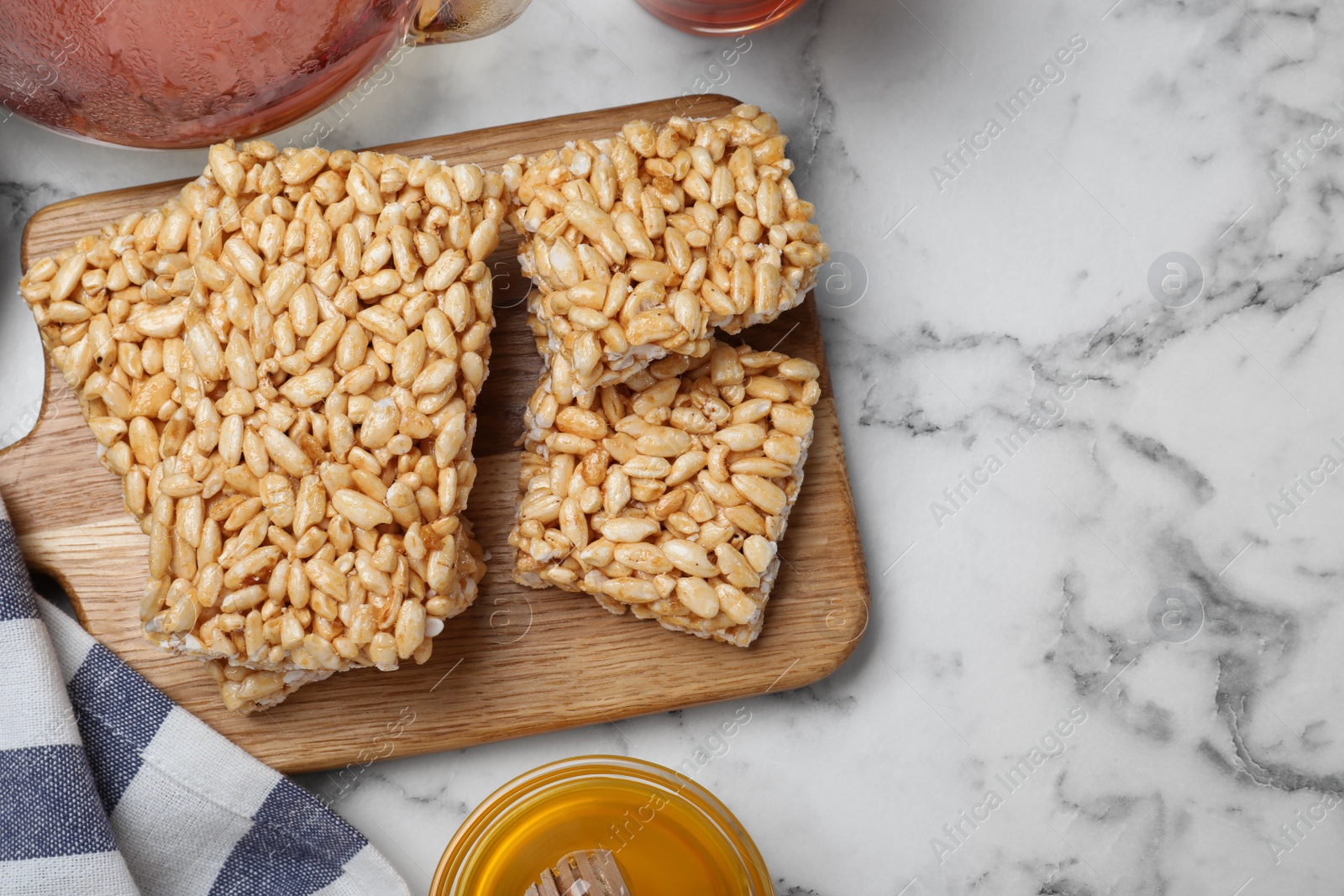 Photo of Delicious rice crispy treats on white marble table, flat lay. Space for text