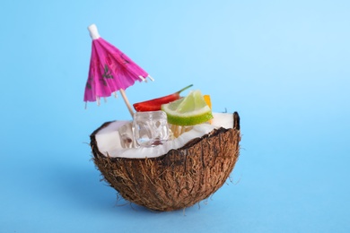 Photo of Summer refreshing cocktail with umbrella in coconut on color background