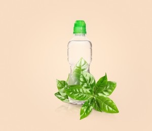Image of Bottle made of biodegradable plastic and green leaves on beige background