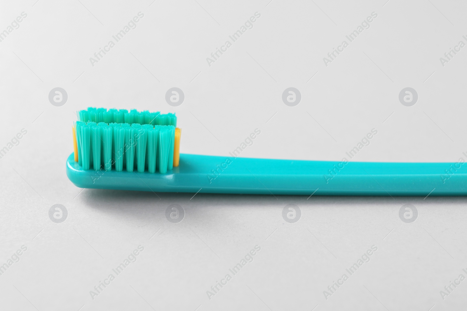 Photo of One plastic toothbrush on light background, closeup