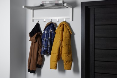Photo of Stylish coat rack on white wall in hallway. Interior design